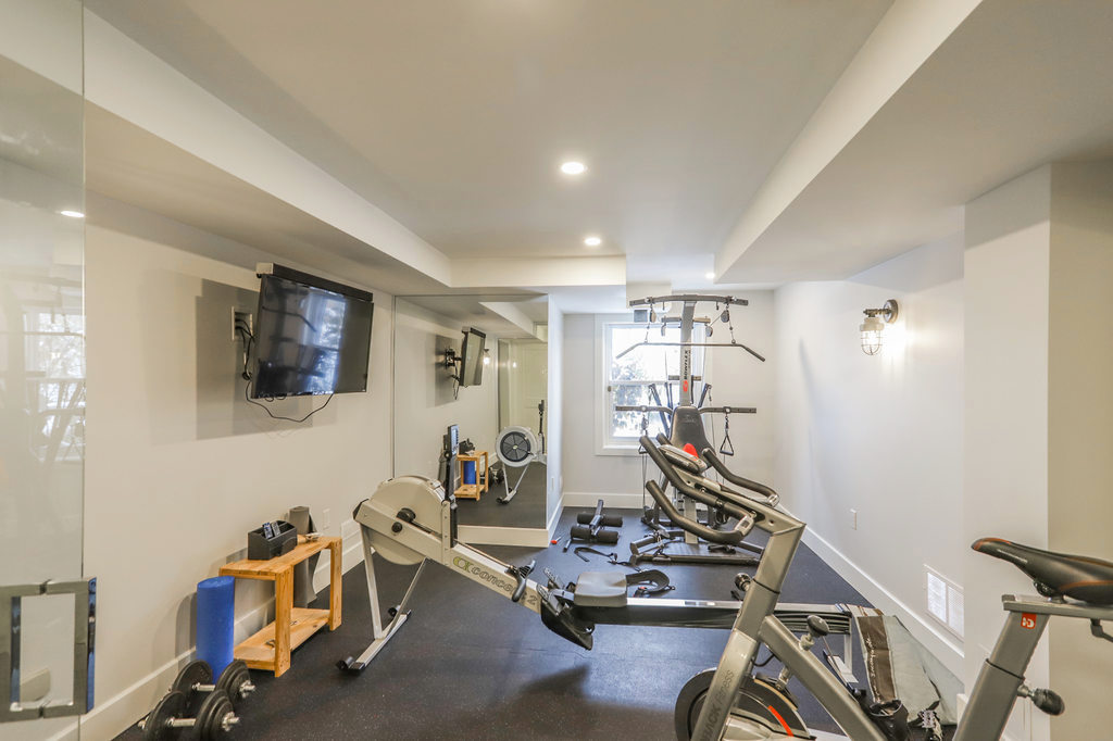 Home gym with exercise machines, bikes, weights, TV and more. A London Ontario home renovation / design / installation project by Core Builders.